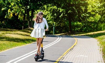 Girl rides an electric scooter in the summer Park
