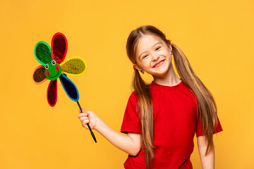 Photo of little cheerful girl happy positive smile hold paper toy windmill isolated over yellow color background. Summer vibes concept