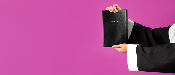 Hands of young Asian nun with Bible on purple background, closeup