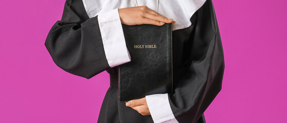 Beautiful young Asian nun with Bible on purple background, closeup