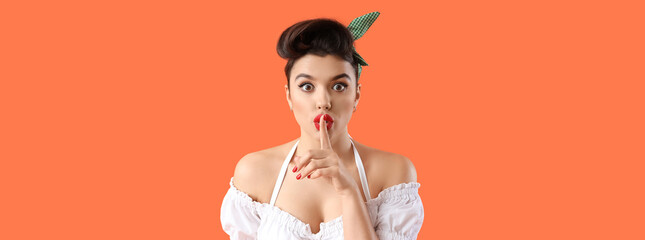 Shocked young pin-up waitress showing silence gesture on orange background, closeup