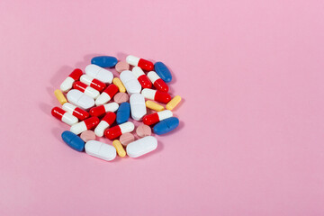 Colorful health palette: medicinal pills arranged on pink background. Copy space