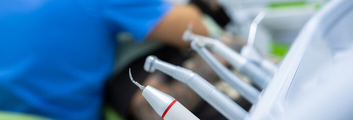 Dentist's medical tools in foreground, dentist working in background, stock photo