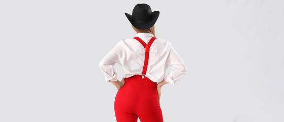 Stylish young woman with suspenders on white background, back view