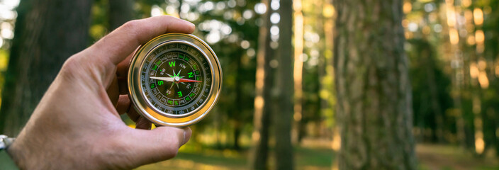 Compass in hand in forest, travel concept
