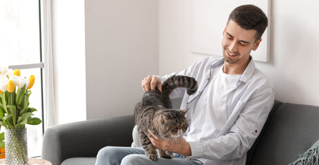 Young man with cute cat in living room