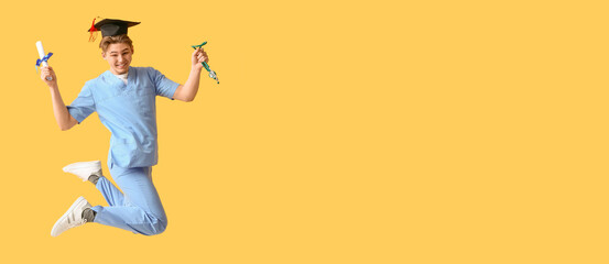 Happy male medical graduate student with diploma and stethoscope jumping on yellow background