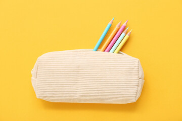 Case with colorful pencils on yellow background
