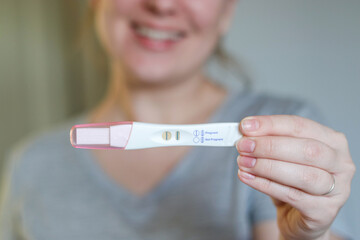 Close up of a happy woman holding a positive pregnancy test