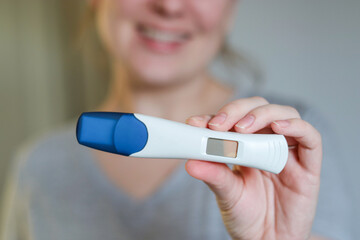 Close up of a happy woman holding a digital positive pregnancy test