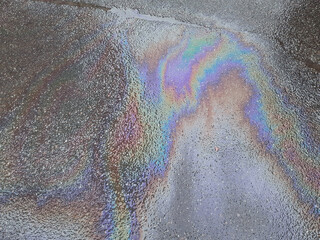 Gasoline fuel stain, gas spill spot or rainbow oil slick on a wet city asphalt road. Urban...