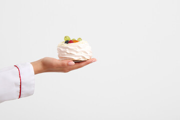 Female confectioner with tasty cake on white background