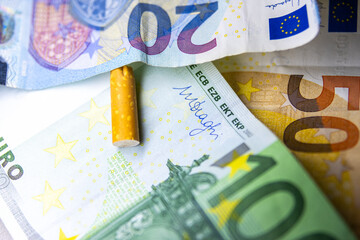 A pack of cigarettes is on top of a stack of euros