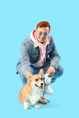 Redhead young happy man taking walk with cute Corgi dog on blue background