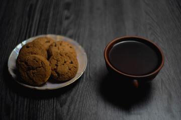 Mug of coffee and plate with cookies on wooden table