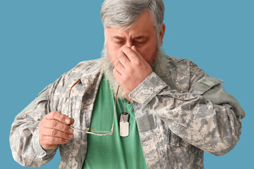 Portrait of sad senior man in military uniform with eyeglasses on blue background - obrazy, fototapety, plakaty