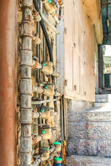 Rusty water pipes with green meters on a stone wall with a slightly open door in the background