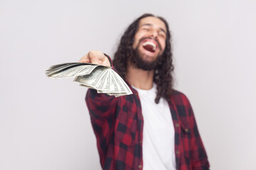 Portrait of joyful cheerful laughing bearded man with long curly hair in checkered red shirt giving...