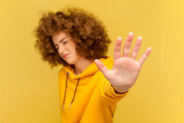 Portrait of scared woman with Afro hairstyle making stop gesture showing palm of hand, conflict...