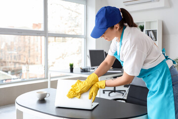 Female janitor cleaning table in office