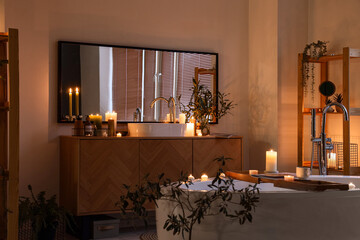 Interior of bathroom with burning candles, sink and mirror in evening
