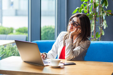 Portrait of smiling satisfied woman working on laptop looking away dreaming about weekend wants to...