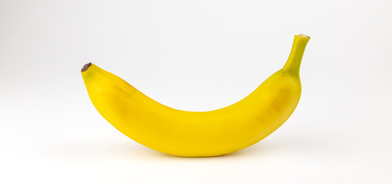 One yellow banana on a white background. The concept of taking vitamins in the summer.