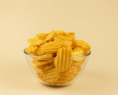 Bowl of potato chips isolated on beige background, Glass bowl with chips.