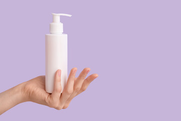 Female hand with bottle of natural cream on lilac background, closeup