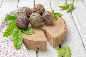 Purple passion fruit with leaves on wooden board