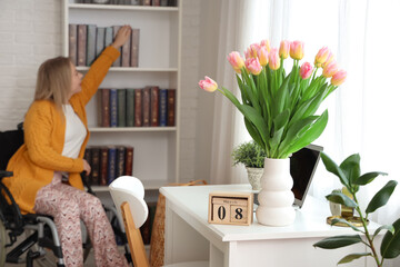 Calendar with date of International Women's Day and tulips on table at home, closeup