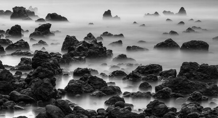 Black and white long exposure of ocean and lava rocks
