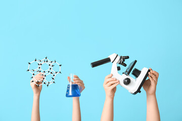 Female hands holding filled flask with microscope and molecular model on blue background. Chemistry...