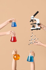 Female hands holding molecular model with microscope and filled flasks on beige background....