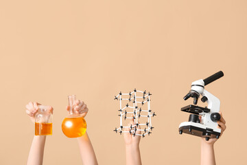 Female hands holding molecular model with microscope, filled flask and bottle on beige background....