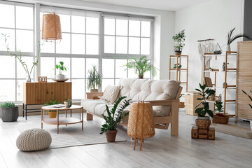 Interior of light stylish living room with comfortable sofa, wooden chest drawer, table,...