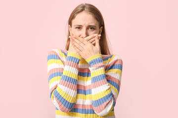 Young woman feeling bad smell on pink background