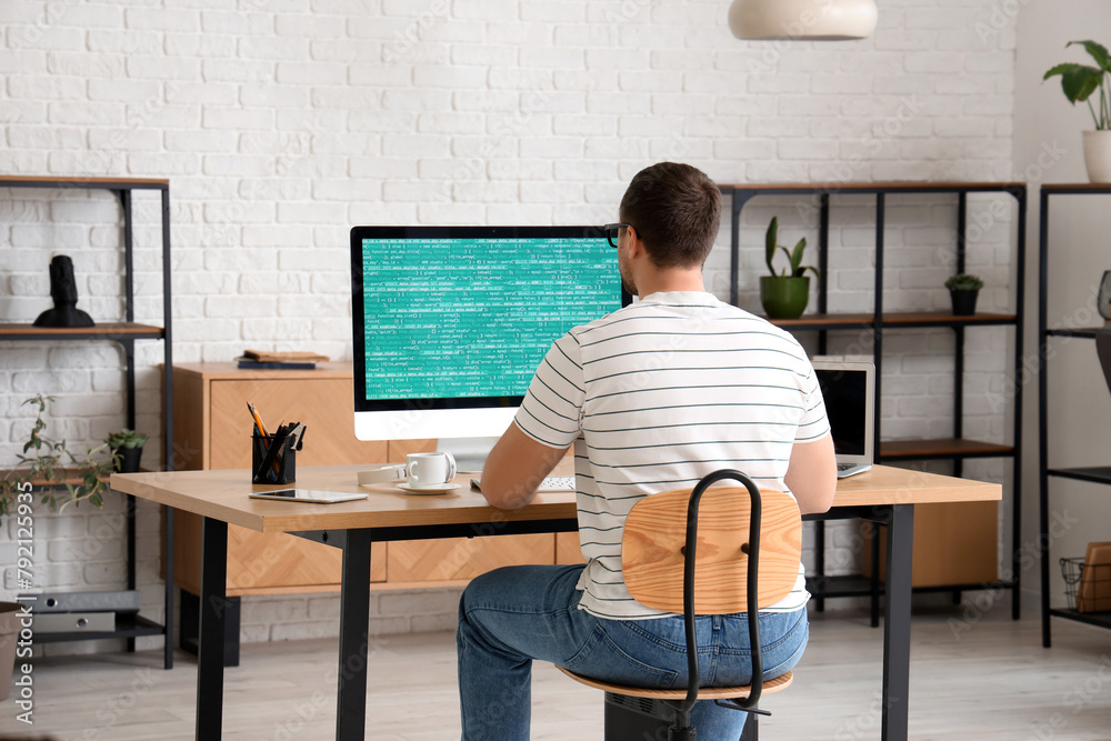 Wall mural male programmer working with computer in office, back view