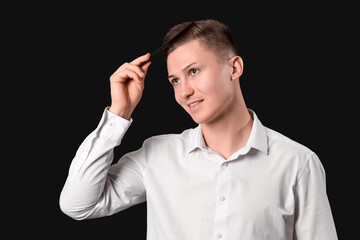 Male barber combing hair on dark background, closeup