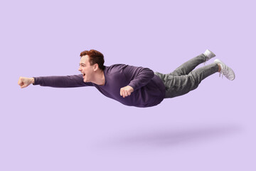 Joyful young man flying on lilac background
