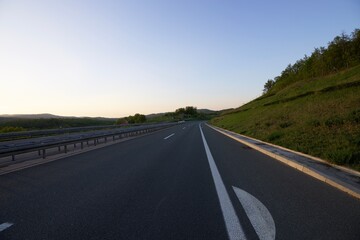motorway in the evening, the road goes into perspective against the blue sky
