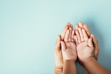 Top view studio shot of family hands stacked on an isolated background. Parents and child holding...
