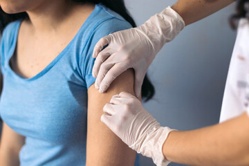 Doctor cleaning arm to give a vaccine to a patient. Close-up hands.