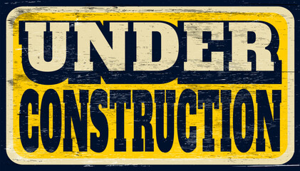 Aged and worn under construction sign on wood