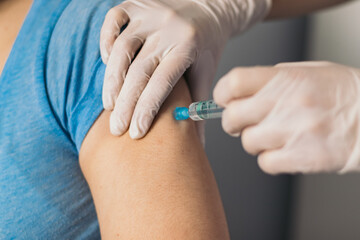 Doctor hands injecting vaccine in the arm of a patient.