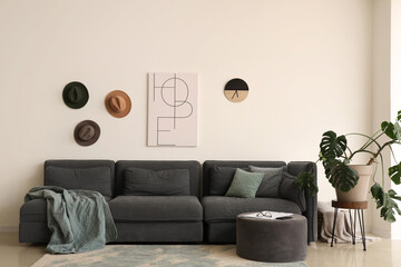 Modern interior of living room with black sofa, pillows, pictures and houseplant