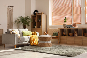 Interior of beautiful living room with sofa, coffee table, shelving units and houseplants