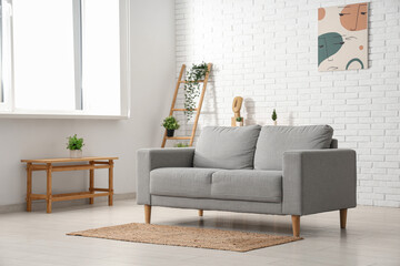 Stylish interior of modern living room with sofa near white brick wall