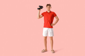 Male lifeguard with binoculars on pink background