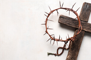 Crown of thorns with wooden cross and beads on white grunge background. Good Friday concept